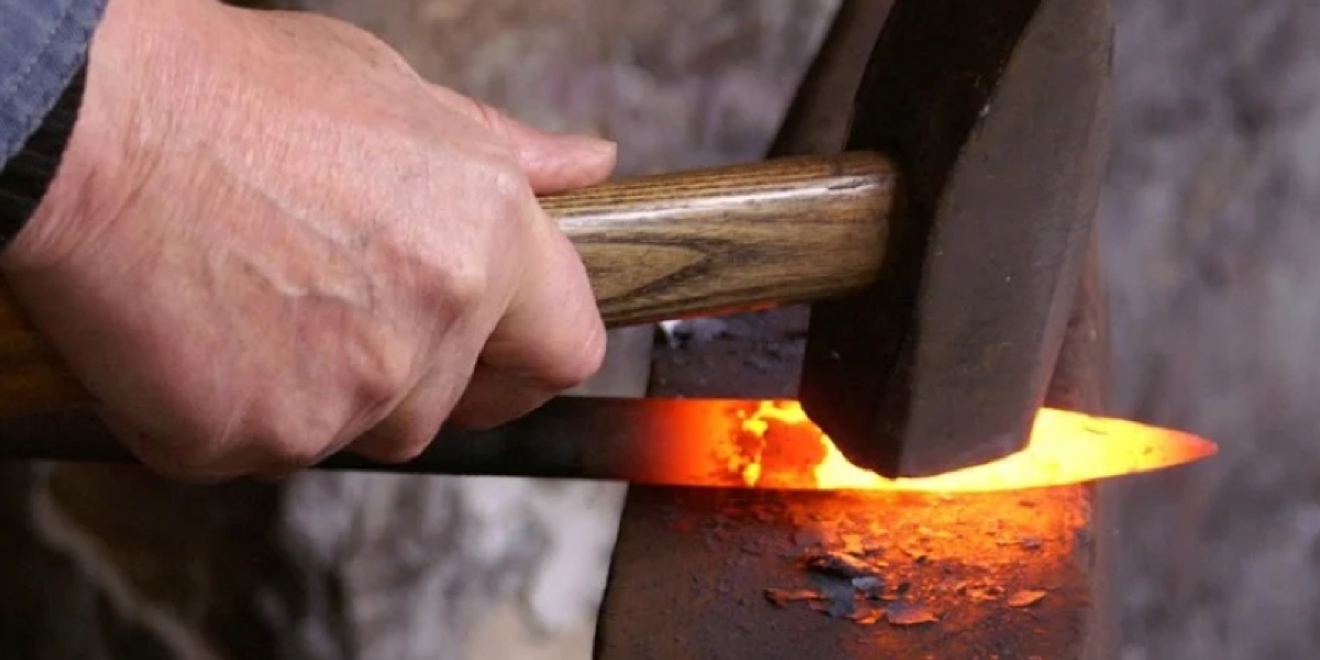 A master Japanese blacksmith hand-forging a glowing red-hot steel blade on an anvil, illustrating the traditional tanren heat treatment of authentic Japanese knives.
