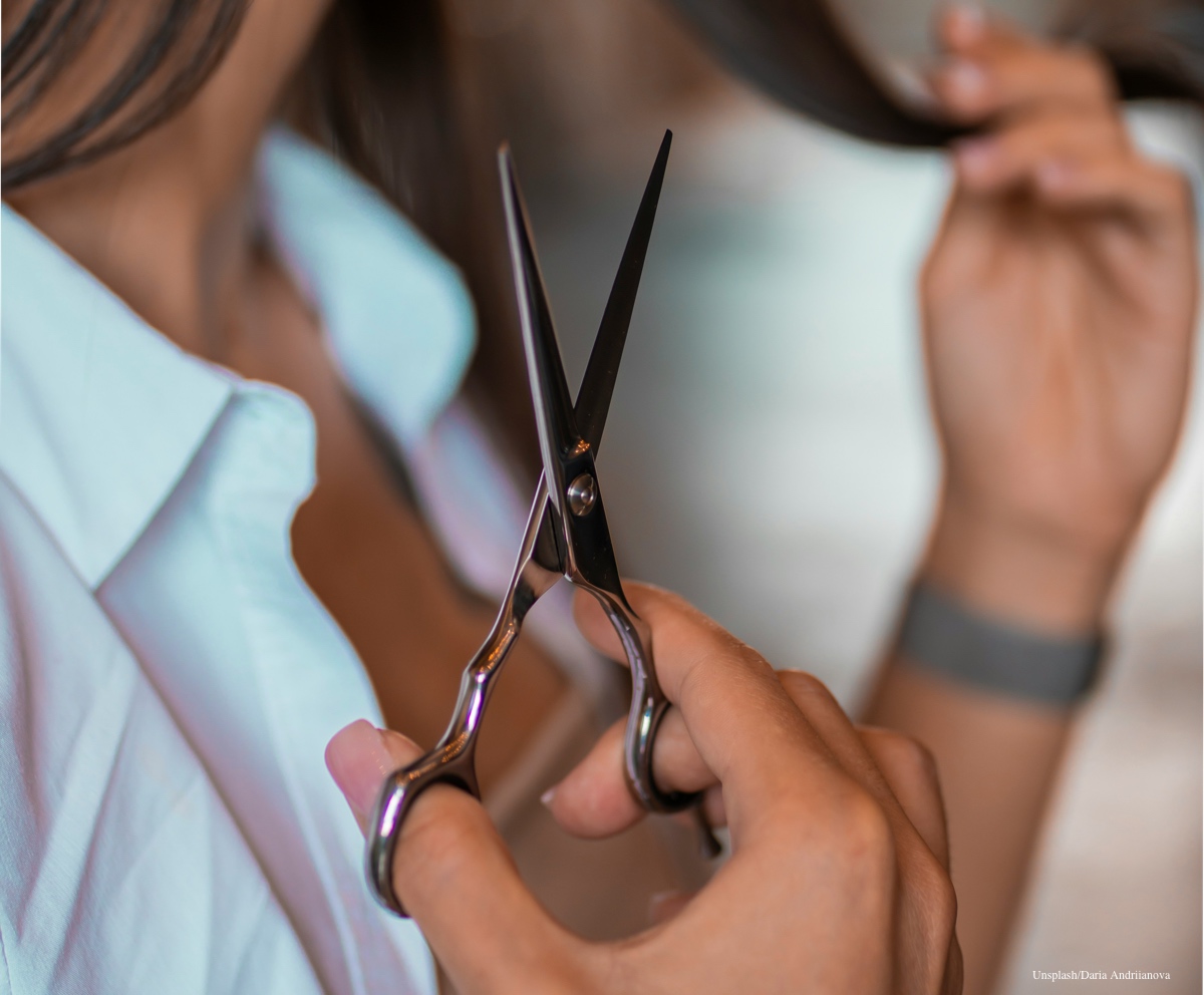 Professional silver Japanese hair shears positioned for a precision cut on dark hair.